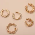 Close-up of multiple gold twisted and chain link cuff earrings on a beige background - Gold Set / Gold