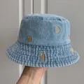 Close-up of children's denim bucket hat with gold shell embroidery detail. - Light Blue Pink Shell