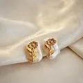 Macro detail of baroque pearl earrings featuring a delicate golden sunflower design - April - Daisy