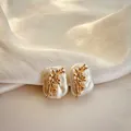 Macro detail of golden flower branch design on natural baroque pearl stud earrings - December - Poinsettia