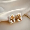 Elegant macro view of gold flower accents on irregular white Baroque pearl earrings - July - Water Lily