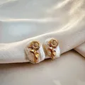 Close-up of elegant gold sunflower earrings featuring natural Baroque pearls on silk - August - Sunflower