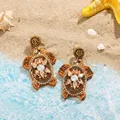 Macro detail of creative handmade seed bead turtle earrings on a scenic beach background - Colorful Sea Turtle Style (22497_4)