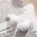 Vue détaillée en gros plan de boucles d'oreilles en émail blanc sur une page de livre ancien. - Blanc