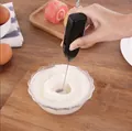 Portable handheld black electric milk frother stirring white foam in a clear glass bowl - Black