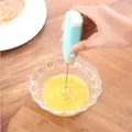 Handheld electric milk frother in mint blue used for mixing coffee and eggs in kitchen - Light Blue