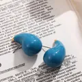 Gros plan détaillé de boucles d'oreilles gouttes d'eau peintes en bleu sarcelle sur livre - Cyan