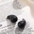 Gros plan de boucles d'oreilles noires en forme de goutte sur une page de livre ancien. - Noir Miroir