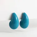 Gros plan d'élégantes boucles d'oreilles puces en émail goutte bleu paon sur fond blanc - Bleu sarcelle