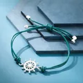 Dettaglio di un bracciale in pelle verde acqua intrecciato con ciondolo timone in argento. - Timone Ciano Scuro