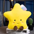 Soft yellow star plush toy with a cute smiling face and rainbow bow sitting on books - Star / S
