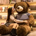 Giant brown teddy bear plush toy wearing a striped sweater in a cozy library setting. - Rose Velvet Dark Brown + Blue and White Sweater / 100cm