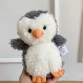 Adorable peluche de pingouin gris et blanc tenue à la main pour la présentation - Pingouin