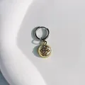 Nahaufnahme eines goldenen Chrysanthemen-Anhängers an einem polierten silbernen Ohrreif. - Runder Sternreif / Gold
