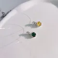 Close-up of yellow and green star-shaped crystal pendants on a minimalist white surface - Gold Tennis Chain