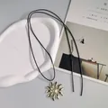 Vista dettagliata di una collana a corda lunga vintage con ciondolo a fiore d'oro pieghettato - Fiore Grande / Oro