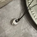 Detailaufnahme einer minimalistischen silbernen Tropfenkette an einer langen schwarzen Schnur - Bohnenanhänger (Schwarze Wachsschnur) / Silber Stil