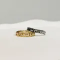 Nahaufnahme goldener und silberner Edelstahlringe mit hohlem griechischem Muster - Größe 7 / Gold Greca-Muster