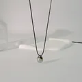 Nahaufnahme des eleganten eiförmigen Metallanhängers an einem minimalistischen Choker - Wachsschnur Wassertropfen-Stil / 85cm Schwarze Schnur