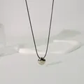 Nahaufnahme eines metallischen geometrischen Anhängers an einer minimalistischen Wachsschnur - Wachsschnur Quadrat-Stil / 85cm Schwarze Schnur