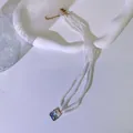 Detaillierte Nahaufnahme einer dreireihigen Perlenkette mit Ozean-Emaille-Anhänger. - Seestern Muschel / Blau/Gold