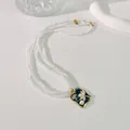 Detailansicht einer Vintage-Perlenkette mit drei Strängen und einem Blumenanhänger - Lotus / Blau/Gold