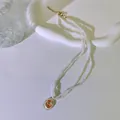 Nahaufnahme einer französischen Vintage-Perlenkette mit einem floralen Rosenanhänger - Orangefarbene Rose / Orange/Rosa