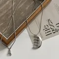 Primer plano detallado de un collar con colgante de peine de acero inoxidable plateado - Cadena serpiente / Plateado