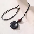 Minimalistische Halskette mit schwarzem Donut-Anhänger und einer roten Holzperle - Friedensschnalle-Stil / Schwarz