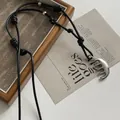 Close-up of a silver comb pendant on a black adjustable cord necklace - Knotted Black Wax Cord / Silver