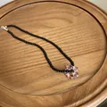 Detaillierte Ansicht einer schwarzen Perlenkette mit rosa Glasblume auf einem Holztablett - 40+5cm / Schwarze Perlenkette Rosa Blume