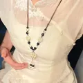 Nahaufnahme einer Vintage-Halskette mit Keramikblume im ethnischen Stil am Modell - Antik Stil Quaste Weiße Blume