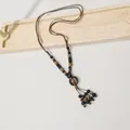 Detailaufnahme der ethnischen langen Keramikperlenkette mit Quaste für einen Vintage-Look - Kaffee Schwarz Perlen Holzring Quaste