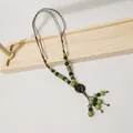 Detailansicht einer ethnischen Vintage-Keramikperlenkette auf einem Holzständer. - Grün Blau Perlen Holzring Quaste