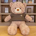 Large cuddly tan teddy bear plush toy wearing a striped sweater in a home setting - Light Brown with Brown Stripes