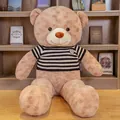 Giant teddy bear plush toy wearing a classic striped sweater in a warm home setting - Light Brown Black Stripe