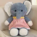Adorable blue plush elephant doll wearing a pink corduroy dress sitting on a cozy sofa - Elephant