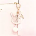 Close-up of cat-shaped dreamcatcher keychain with white plush ball and gold hardware - Cat Head / Off White