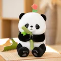 Soft plush giant panda doll holding bamboo with a decorative pink flower on its head - Hua Hua Holding Bamboo / Sitting Height 30cm
