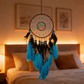 Turquoise tree of life dreamcatcher with vibrant blue feathers hanging in a cozy bedroom - Blue