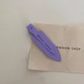Detailed close-up of a purple ribbed metal alligator hair clip on a canvas background - Purple