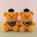 Detalle de dos osos de peluche de graduación con birretes y bandas coloridas de felicitación. - Oso de Mantequilla de Graduación
