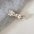 Detail shot of a cream-colored polka dot bow hair tie on gray fuzzy knit fabric - Duckbill Hair Clips / Beige Polka Dot