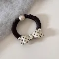 Detailed macro view of an elegant black scrunchie hair tie with pearl and polka-dot bow - Pearl Scrunchie / Beige Polka Dot