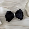 Detailed close-up of a vintage black satin hair clip with elegant pearl center embellishment. - Spring Clips