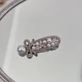 Close-up of luxury pearl bow hair clip with sparkling rhinestones on a mirror surface. - Pearl Bow - Oval Clip