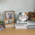 Cute tricolor plush lucky cat doll sitting on books in a cozy home office setting - Fortune Cat / White / 20cm