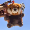 Primo piano di un simpatico portachiavi di peluche panda rosso su sfondo cielo blu - Procione Seduto / 13cm (Con Cordino)