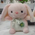 Detailed view of a soft pink plush rabbit wearing a green polka-dot scarf and flower. - 22cm / Pink