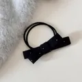 Détail macro d'un élastique à nœud à pois noirs de style français en laine douce - Cravate à cheveux / Noir